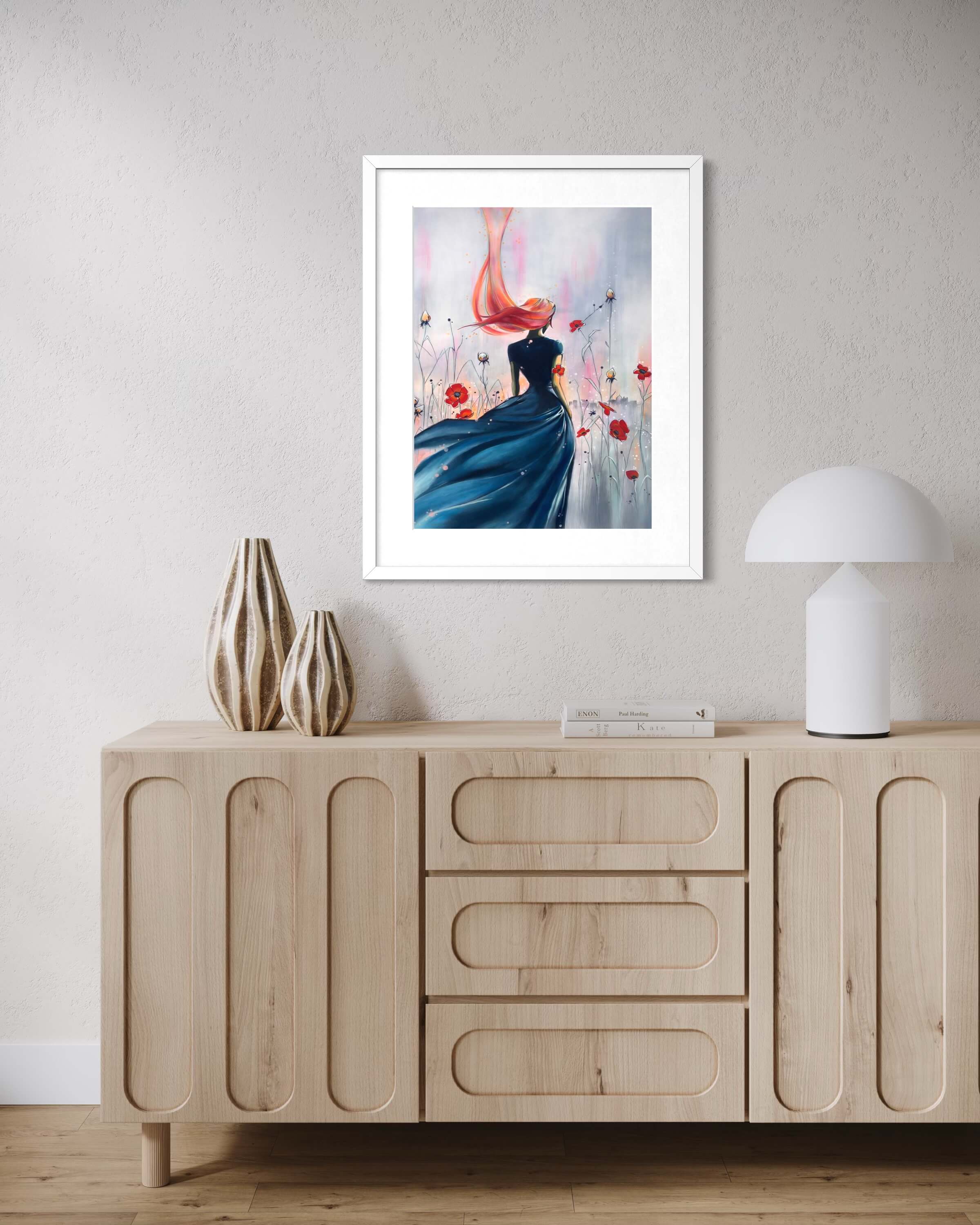 Illustration encadrée représentant une femme de dos à la robe bleue et aux cheveux au vent, entourée de coquelicots rouges, présentée sur fond blanc./
Framed illustration depicting a woman seen from behind in a flowing blue dress with wind-blown hair, surrounded by red poppies, presented on a white background.